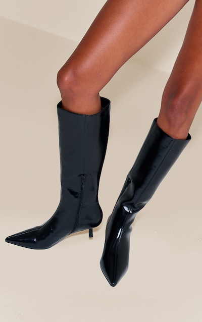 Botte montante noire stretch à bout pointu et petit talon en suédine, avec une doublure en fausse fourrure.