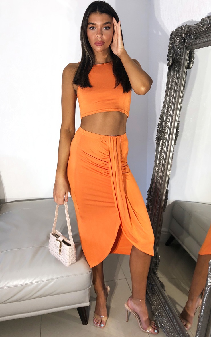 Jupe mi-longue slinky orange à devant drapé