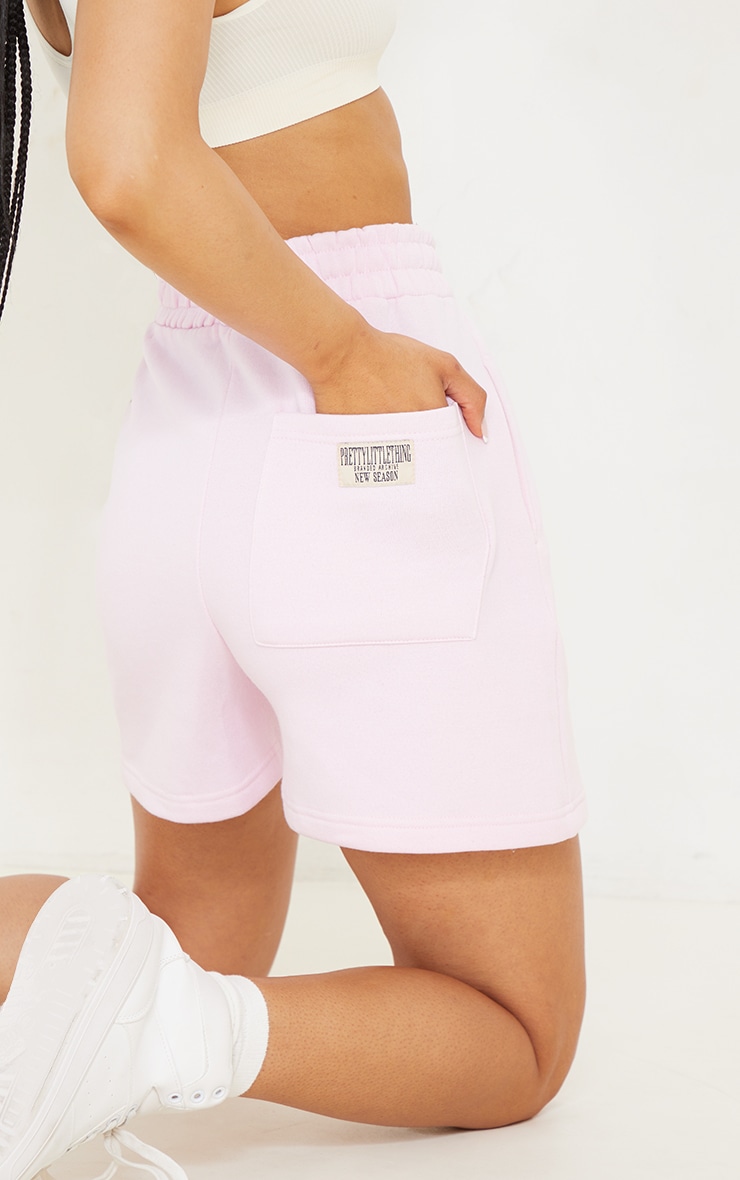 PRETTYLITTLETHING - Short de course rose tendre à badge derrière